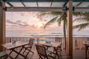 a restaurant with tables and chairs on a balcony with the ocean at Banana Fan Sea Resort in Chaweng