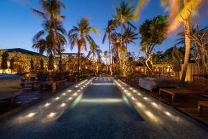 a pool with lights and palm trees at night at Banana Fan Sea Resort in Chaweng