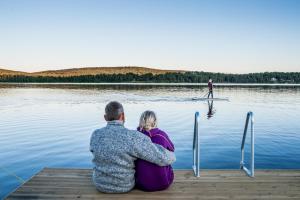 
a man and woman sitting on a wooden bench near the water at Icehotel in Jukkasjärvi
