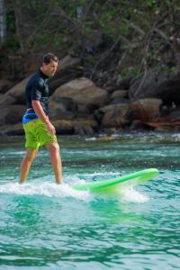 a man standing on a surfboard in the water at Bay Hiriketiya in Hiriketiya