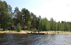 un barco en la orilla de un lago con gente en Camping Toivolansaari, en Ikaalinen