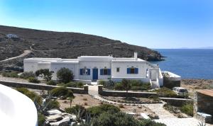 una casa blanca en una colina junto al océano en Villa Areti, en Tinos