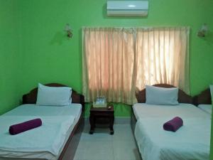 two beds in a room with green walls at Sam So Guesthouse in Siem Reap
