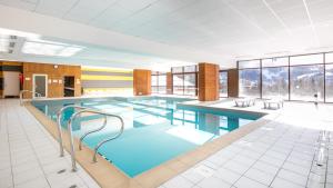 a large swimming pool with twothirds of the room with windows at Vacancéole - Le Hameau de Valloire in Valloire