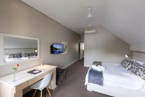 Dormitorio con cama, escritorio y cama en Quarry Lake Inn en East London