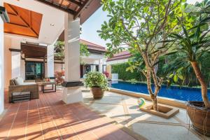 an outdoor living room with a pool and trees at Jewels Villas Phuket in Bang Tao Beach