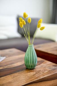 a green vase with yellow flowers sitting on a table at Ferienwohnung Mahlsdorf-Ein Quäntchen mehr in Berlin