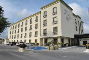 un gran edificio blanco con coches aparcados en un aparcamiento en Hotel Alameda Express, en Matamoros