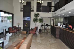 a lobby with a bar and a woman sitting at a desk at Hotel Alameda Express in Matamoros