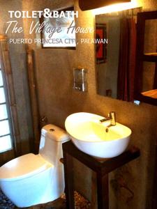 a bathroom with a sink and a toilet and a mirror at The Village House in Puerto Princesa City