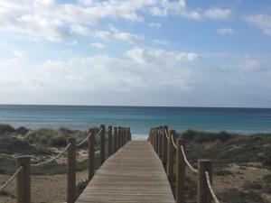 a wooden boardwalk leading to the ocean on a beach at Apartamento el Descanso in Son Bou