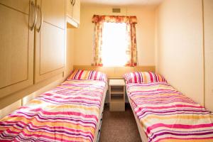 2 camas en una habitación pequeña con ventana en Mobile homes Marina Liptov en Bešeňová