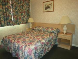 Habitación de hotel con cama y mesa con lámpara en Tropicana Suite Hotel en Vancouver