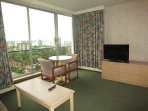 a living room with a table and a tv and windows at Tropicana Suite Hotel in Vancouver