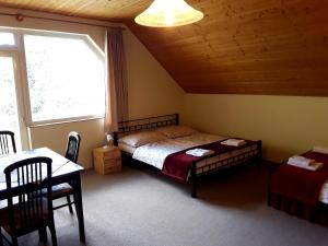 Schlafzimmer mit einem Bett, einem Tisch und einem Fenster in der Unterkunft Villa Hedi Panzió in Dunakiliti