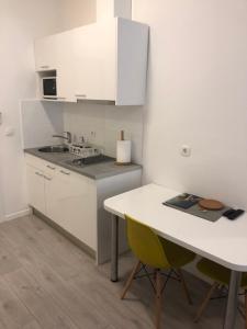 une cuisine avec des armoires blanches, une table et un évier dans l'établissement Apartment Perla, à Zagreb