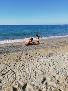a man and a child playing on the beach at Villa Calipso in Furnari