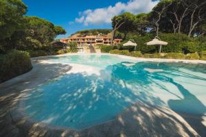 a swimming pool with blue water in front of a house at Roccamare Resort - Casa di Ponente in Castiglione della Pescaia