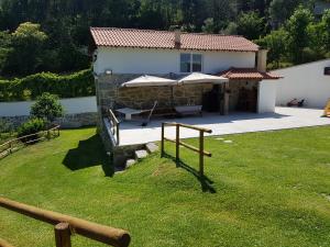 ein Steinhaus mit Sonnenschirmen im Hof in der Unterkunft Quinta da Tormenta -14 pessoas- Cabeceiras de Basto 2 casas e piscina privada in Cabeceiras de Basto