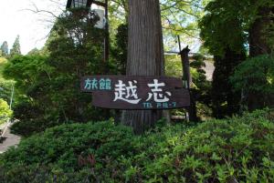 a sign with asian writing on it next to a tree at Oshi Ryokan in Nagano