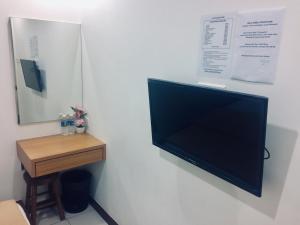 a flat screen tv hanging on a wall next to a table at Api-Api GuestHouse in Kota Kinabalu