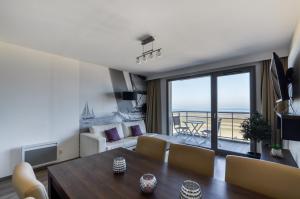 een woonkamer met een eettafel en uitzicht op de oceaan bij Evancy Etoile de Mer in Bray-Dunes