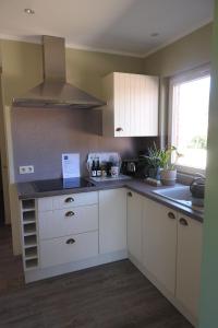 a kitchen with white cabinets and a sink at t Sutterhuisje, zalig slapen aan het Donkmeer in Donk