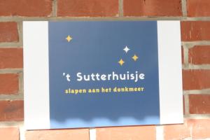 Donk的住宿－t Sutterhuisje, zalig slapen aan het Donkmeer，砖墙上的一个标志,上面写着刀剑,发热