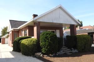 a brick house with bushes in front of it at t Sutterhuisje, zalig slapen aan het Donkmeer in Donk