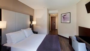 a bedroom with a large white bed and a television at TURIM Luxe Hotel in Lisbon