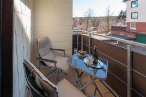 einen Balkon mit einem Tisch und Stühlen sowie einer Flasche Wein in der Unterkunft Harznest in Braunlage