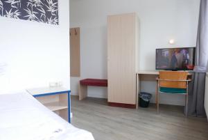 a room with a bed and a desk and a tv at Hotel Best one in Roßdorf