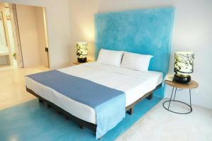1 dormitorio con 1 cama grande y pared azul en Kocchira en Hua Hin