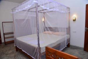 ヒッカドゥワにあるVilla Wanderlustのベッドルーム(白いシーツを使用した天蓋付きベッド1台付)