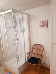 Cette chambre comprend une douche et une chaise en bois. dans l'établissement Quai Peree Apartement, à Saint-Valery-sur-Somme