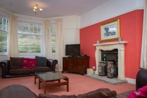 a living room with red walls and a fireplace at Stanley House in Eskdale