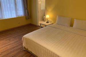Un dormitorio con una gran cama blanca y una lámpara en American Village Resort en Taipéi