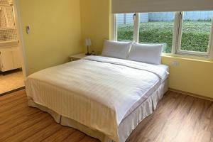 sypialnia z dużym białym łóżkiem i oknem w obiekcie American Village Resort w Tajpej