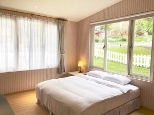 una camera da letto con un letto grande e una grande finestra di American Village Resort a Taipei