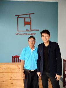 two men are standing in front of a table at บ้านรวมสุข the Happiness in Chiang Kham