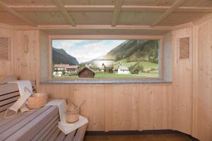 a window in a wooden room with a view of a village at Bio Hotel Stillebach in Sankt Leonhard im Pitztal