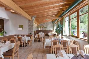 um restaurante com mesas e cadeiras brancas e janelas em Bio Hotel Stillebach em Sankt Leonhard im Pitztal