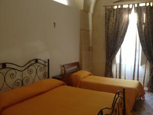 1 dormitorio con 2 camas y una cruz en la pared en B&B Regina Maria, en Lecce