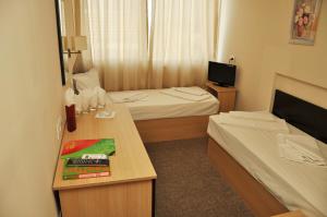 a small hotel room with two beds and a desk at Hotel Flora in Mamaia