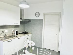 a kitchen with white cabinets and a clock on the wall at My ROMAN DREAM in Rome