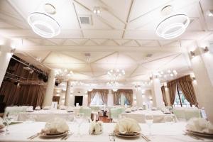 基輔的住宿－科里巴別墅酒店，用餐室配有白色桌椅和吊灯。