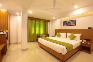 een slaapkamer met een groot bed en een groen gordijn bij Hotel Park Residency in Kozhikode