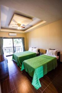 a hotel room with two beds and a window at Minshuku KCS Hotel and Restaurant in Puerto Galera