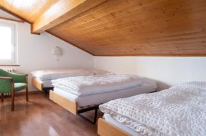 two beds in a room with a wooden ceiling at Hotel Schwarzsee in Zermatt