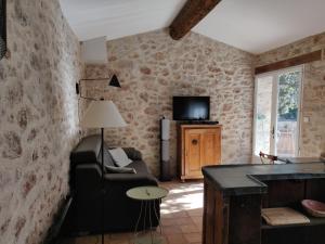 een woonkamer met een bank en een tv bij Le Bastidon - La Luberonne in Lourmarin
